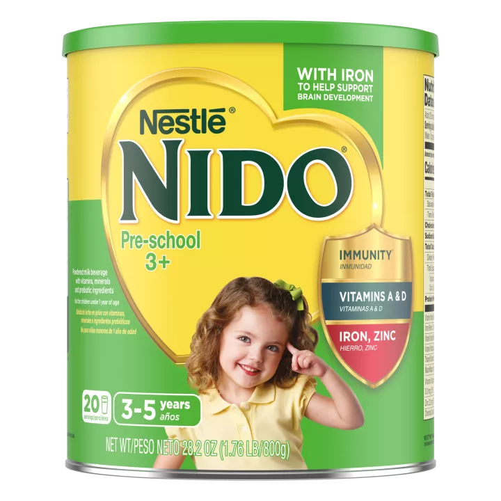 A canister of Nido 3+ with an “immunity, Vitamins A, & D, Iron, and Zinc” badge near a young girl smiling and pointing.