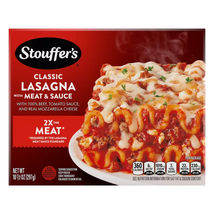 A plate of Lasagna with Meat & Sauce on a table below the product name, STOUFFER'S logo and "2x the Meat" label.