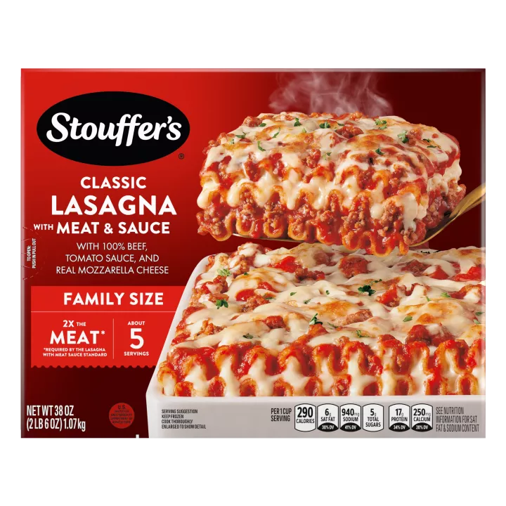 A plate of Lasagna with Meat & Sauce beside a red dish of lasagna on a table below the product name and "2x the Meat" label.