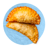Primer plano de un par de empanadas sobre un fondo azul.