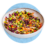 Close up of a vegetarian salad in a white bowl, on a blue background.