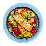 Overhead of a green salad in a black bowl with a piece of salmon on top, on a blue background.