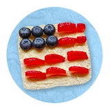 Memorial day snack cracker designed with blueberries and strawberries to look like the U.S. flag, on a blue background.