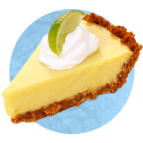 Close up of a slice of key lime pie with a dollop of whipped cream and a lime-quarter on top, on a blue background.