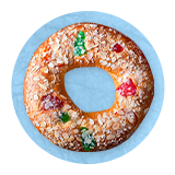Primer plano de una rosca de reyes decorada con colores sobre un fondo azul.