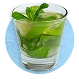 Close up of a mint julep cocktail in a small clear glass with mint leaves for decoration, on a blue background.