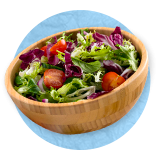 Close up of wooden bowl filled with salad greens, on a blue background.