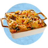 Close up of small white baking dish with copper handles and breakfast casserole in it, on a blue background.