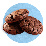 Close up of three chocolate cookies stacked carelessly on each other, on a blue background.