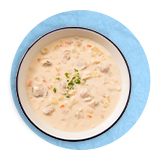 Overhead of a bowl of lobster bisque, on a blue background.