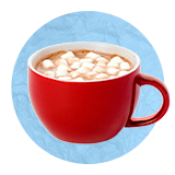 Primer plano de una taza roja con chocolate caliente y mini malvaviscos por encima sobre un fondo azul.