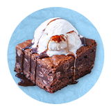 Close up of a brownie sundae, on a blue background.
