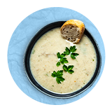 Overhead of a bowl of cream of mushroom soup, on a blue background.
