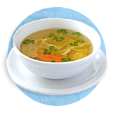  Close up of chicken soup in a white bowl, on a blue background.