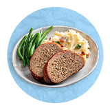 Close up of meatloaf dinner with mashed potatoes and green string beans on a white plate, on a blue background.