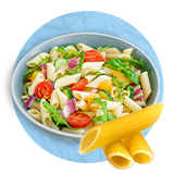 Close up of a pasta salad in a white bowl with loose ziti pasta in front of the bowl, on a blue background.