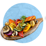  Close up of wooden spoon full of chopped grilled vegetables on it, on a blue background.