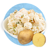 Close up of a potato salad in a blue bowl and a halved potato in front of bowl, on a blue background.