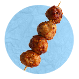 Close up of a skewer with four meatballs on it, on a blue background.