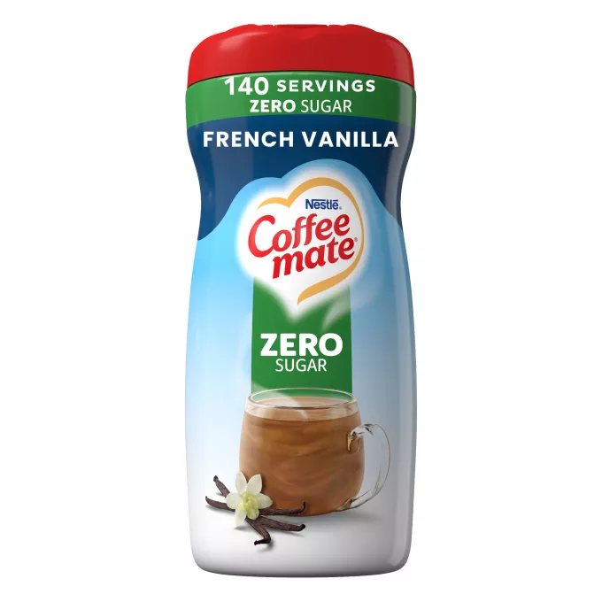 Una lata azul de creamer French Vanilla Creamer con una tapa roja y una etiqueta verde que dice "Sin azúcar" encima de una taza de café y vainas de vainilla.
