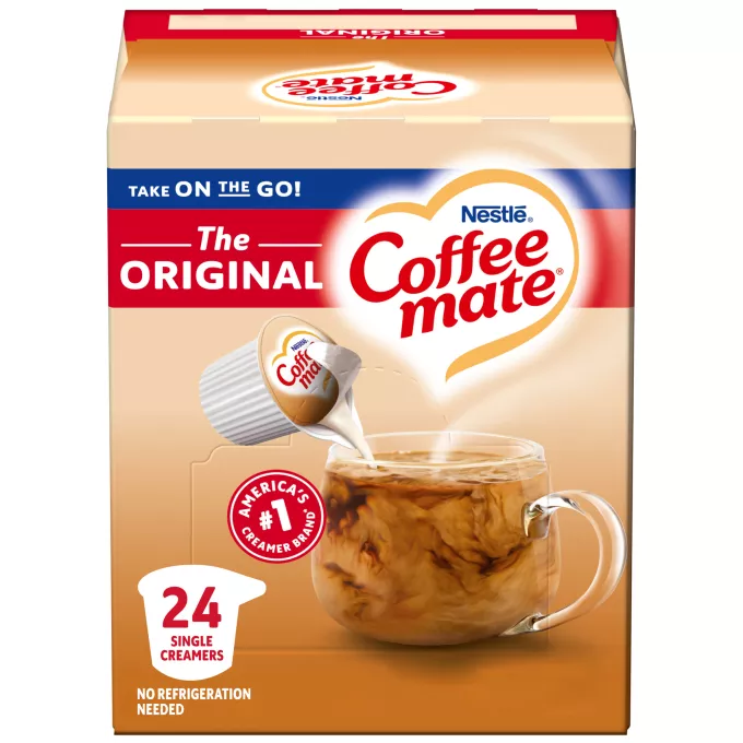 Una caja de porciones individuales de creamer original Coffee mate con una etiqueta roja, una taza de café, un biscotti y el logotipo de Coffee mate.