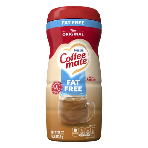 Una lata de creamer en polvo Coffee mate Original sin grasa con una tapa roja y una etiqueta azul encima de una taza de café con un biscotti.