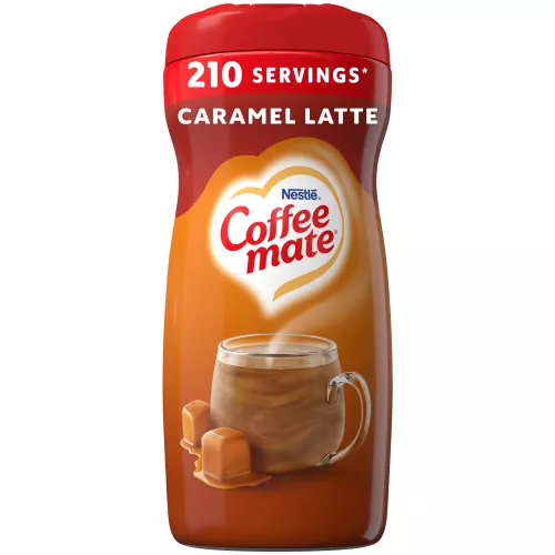 A brown canister of Coffee mate Caramel Latte Creamer with a red label above a mug of coffee with caramel drizzle.