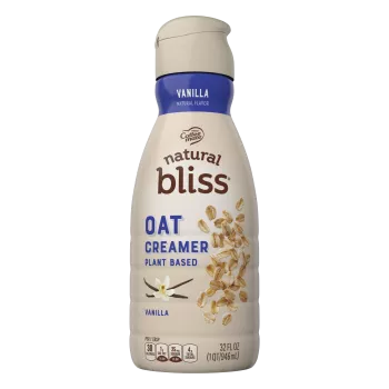 A brown bottle of natural bliss Vanilla Flavored Oat Milk Creamer with a blue label above vanilla beans and oats.