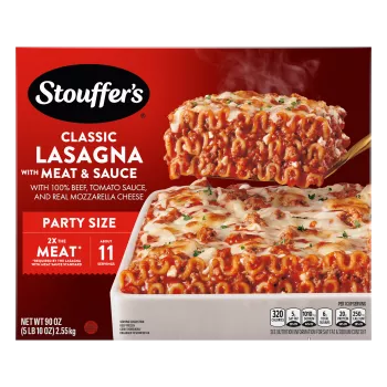 A spatula lifts Lasagna with Meat & Sauce from a red dish on a table with the product name and "2x the Meat" label.