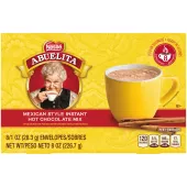 A yellow box with a red label below a yellow mug of Mexican hot chocolate behind cinnamon sticks.