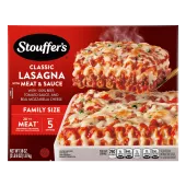 A plate of Lasagna with Meat & Sauce beside a red dish of lasagna on a table below the product name and "2x the Meat" label.