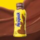 A bottle of NESQUIK chocolate milk on a wave of chocolate milk. 