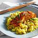 Glazed salmon over yellow seasoned rice on a blue plate with chopsticks.